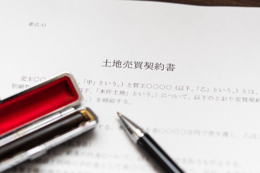土地の売買契約書の上に置かれた判子とボールペン。