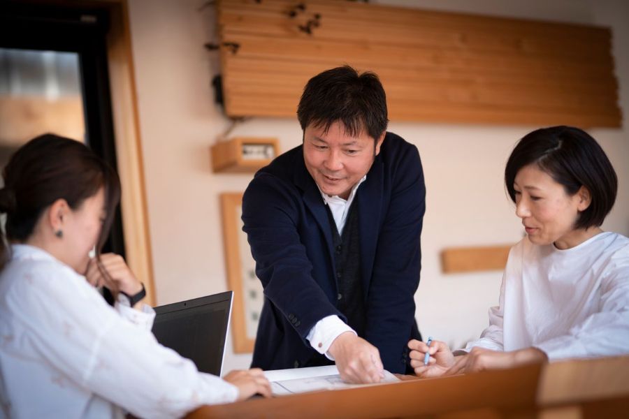 家づくりの打ち合わせをするスーツの男性と白いシャツの女性2人